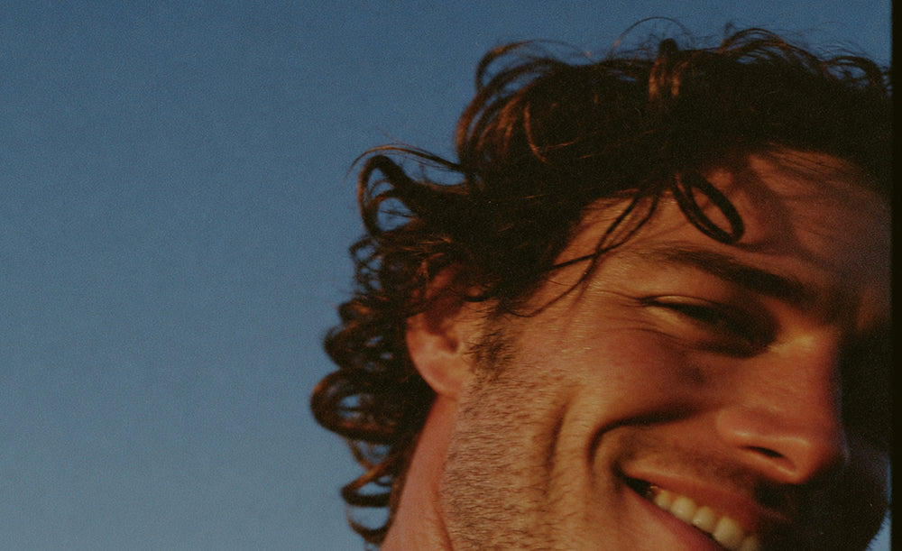 Close up of side of mans face, with curly hair and a stubbly beard.